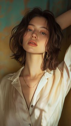 Woman with short wavy hair and a gold necklace in soft lighting