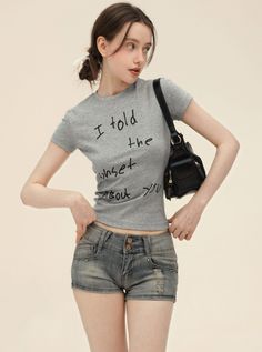 Woman in a gray crop top and denim shorts with a black handbag