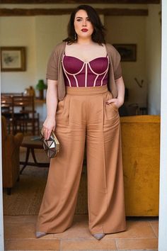 Woman in a burgundy corset top and wide leg pants holding a geometric clutch