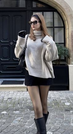 Woman in a turtleneck sweater, mini skirt, and boots on a cobblestone street