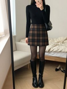 Person in a black turtleneck and plaid skirt with knee-high boots