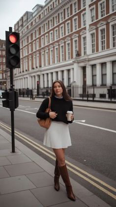 Woman in a white pleated skirt and black sweater walking on a city street