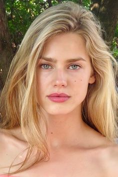 Close-up portrait of a woman with blonde hair and blue eyes outdoors