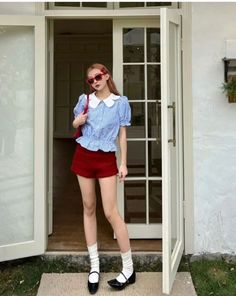 Woman in red shorts and a blue striped shirt standing in a doorway