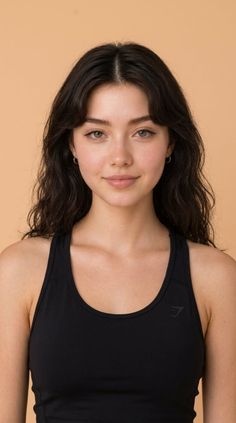 Woman with long dark hair wearing a black sport top against a plain background
