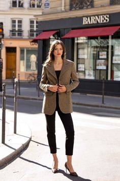 Woman in a brown blazer and black pants standing on a city street
