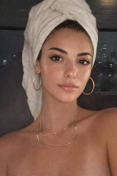 Woman with a towel wrapped around her head, wearing hoop earrings and a gold necklace