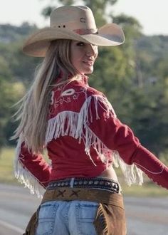 Woman in a cowboy hat and red fringe jacket looking over her shoulder