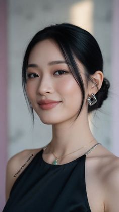 Woman with black hair in an updo wearing a black top and jewelry
