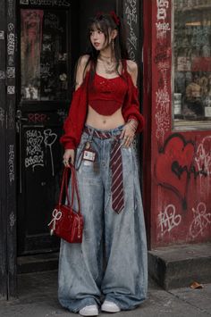 Woman in a red crop top and baggy jeans standing in front of a graffiti-covered wall