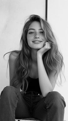 Smiling woman with long hair and freckles, wearing a tank top and jeans