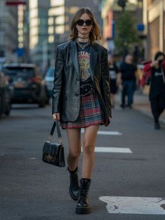 Woman in a plaid skirt and leather jacket walking on a city street