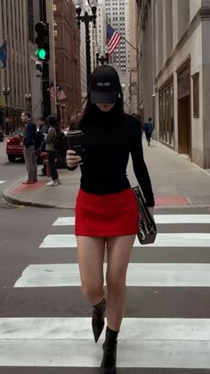 Woman in a red mini skirt and black turtleneck crossing a city street