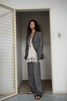 Woman in a gray suit and lace top standing in a doorway