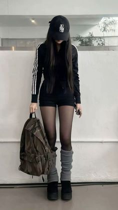 Person in black athletic wear, cap, and leg warmers holding a camouflage backpack