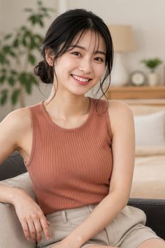 Woman with black hair in an updo wearing a ribbed tank top and light shorts indoors