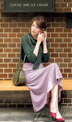 Woman with short hair sitting on a bench, adjusting her earring