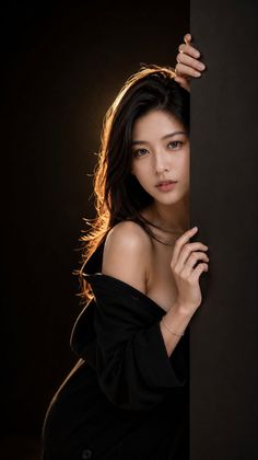 Woman with long dark hair and exposed shoulders peeking from behind a wall