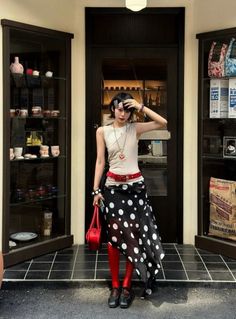 Woman with short hair wearing a polka dot skirt and red tights outdoors