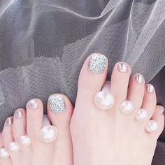 Feet with rhinestone and silver pedicures, separated by pearl-like toe separators