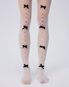 Legs wearing white fishnet stockings with black bows on a white background