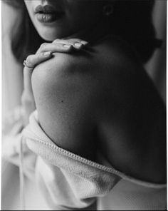 Woman with exposed shoulder and hand on her collarbone in dramatic lighting