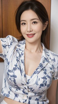 Woman with short hair wearing a white and blue patterned shirt, smiling indoors