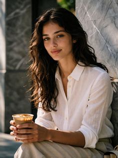 Woman with long wavy hair and freckles holding a coffee cup outdoors