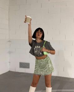 Woman in a crop top and zebra print skirt holding a coffee cup