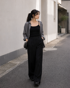 Woman with a ponytail wearing a loose shirt and wide leg pants walking on a street