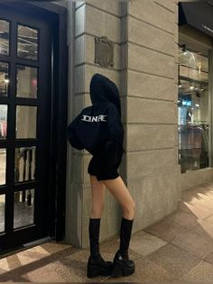Person in a black hoodie, short shorts, and platform boots at night