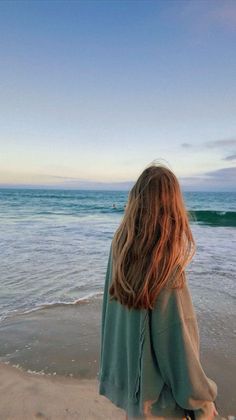 Person with long hair looking at the ocean at sunset