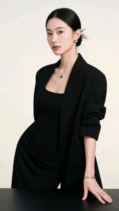 Woman in a black blazer and dress with an updo and jewelry in a studio shot