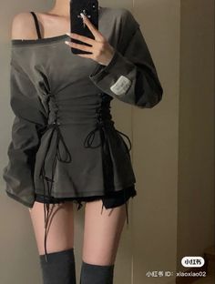 Person in an off-shoulder top with corset detail and short shorts taking a mirror selfie