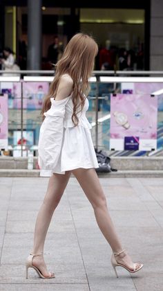 Woman in a white dress and high heels walking outdoors