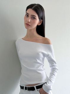 Woman with long black hair wearing a white off-shoulder top and white pants