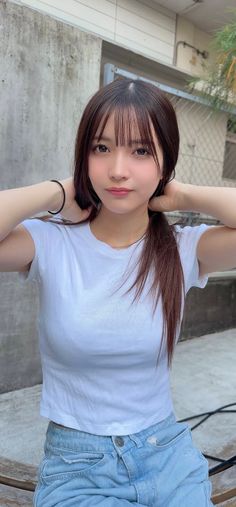 Woman with long hair and bangs wearing a white t-shirt and denim shorts outdoors