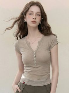 Woman with long wavy hair and freckles wearing a v-neck shirt and pearl earrings