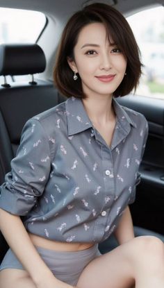 Woman with short hair and earrings in a car, wearing a patterned shirt