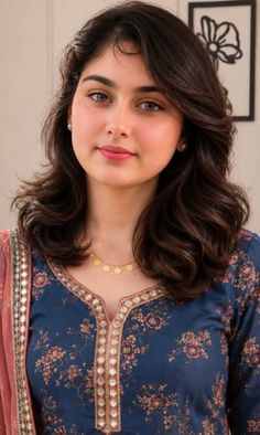 Woman with dark wavy hair wearing a floral dress and gold necklace