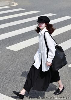 Woman in a black hat and white shirt walking on a crosswalk