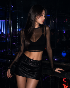 Woman in a black mesh top and mini skirt in a club with neon lighting