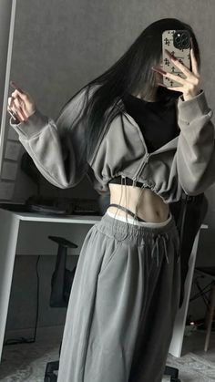 Person with long dark hair taking a mirror selfie, showing midriff
