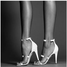 Woman's legs in white strappy high heels in a studio shot