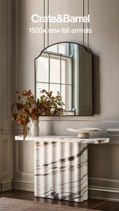 Marble console table with a mirror and plant arrangement in an indoor setting