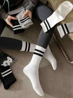 Person wearing gray leggings and white striped socks, holding more socks