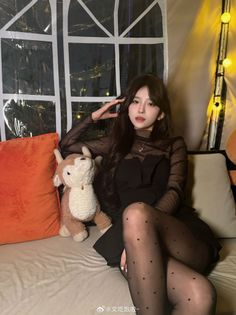 Woman in a black dress and polka dot tights sitting indoors