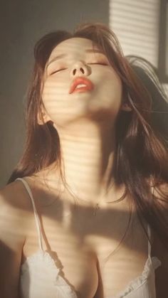 Woman with long hair and cleavage in a white top with dramatic lighting