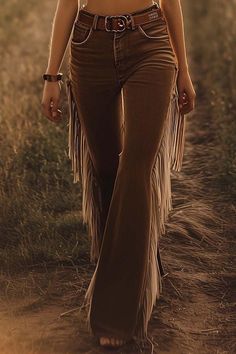 Person in fringe pants and a leather belt walking outdoors at golden hour