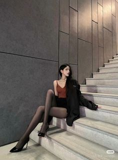 Woman in a rust-colored top, black shorts, and tights sitting on outdoor stairs